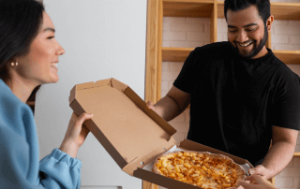 Hombre repartiendo pizza en una caja abierta, representando el reparto de pizza y la importancia de los equipos y tecnologías que aumentan el beneficio de la operación.