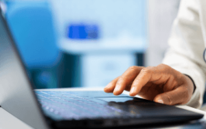 Médico digitando em um notebook acessando um software hospitalar.