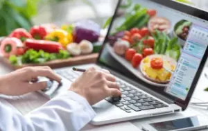 Aluna de nutrição analisa dados de gestão em software Teknisa durante aula prática na universidade.