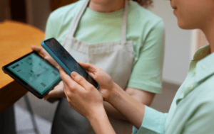Duas pessoas segurando um tablet e um smartphone exibindo o melhor sistema para restaurante.