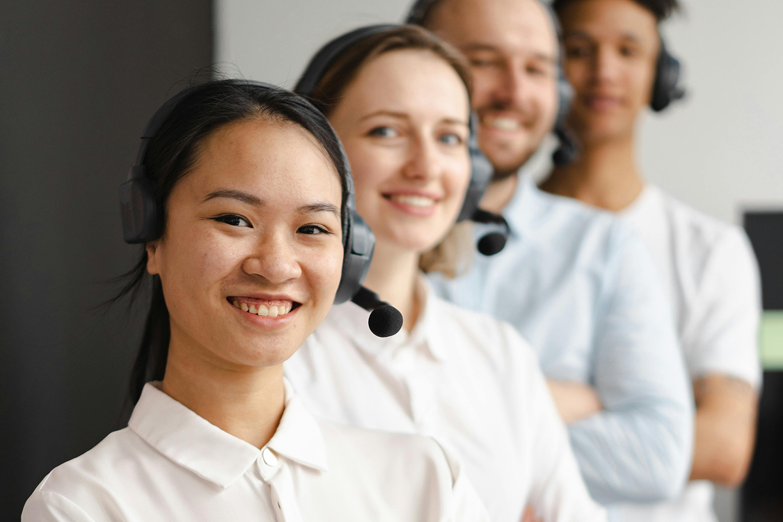 Equipe de atendimento ao cliente sorrindo usando headsets.
